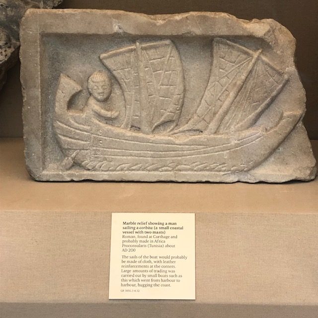 Photo of a marble relief of a man sailing a small boat with two sails. 