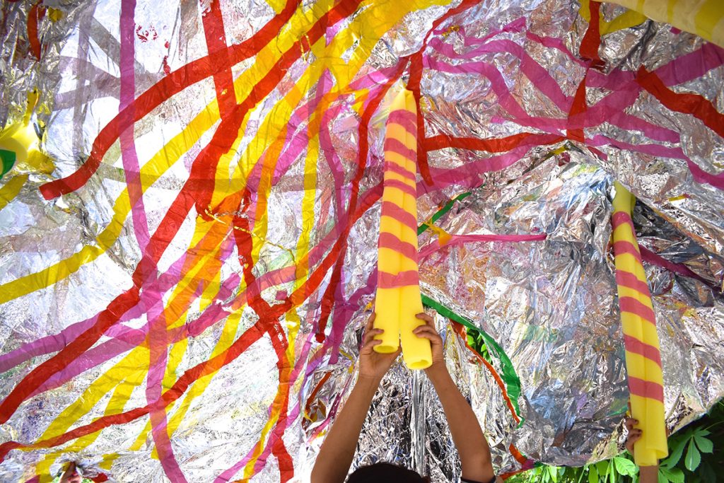 Large foil sheet covered in coloured tape. Help up in the centre by two arms and yellow foam tubing.