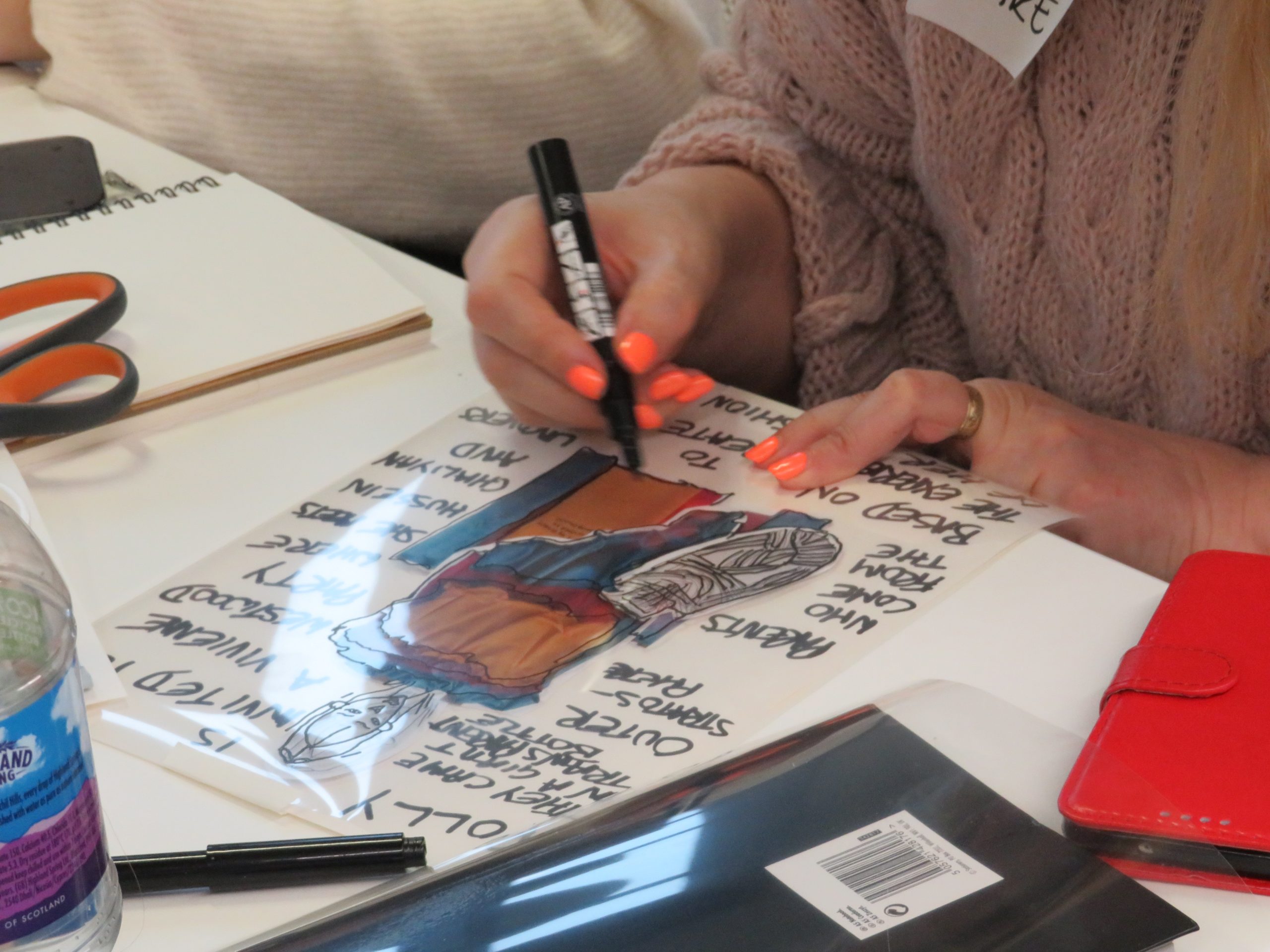 A close up of a woman's hands working on a graphic drawing. 