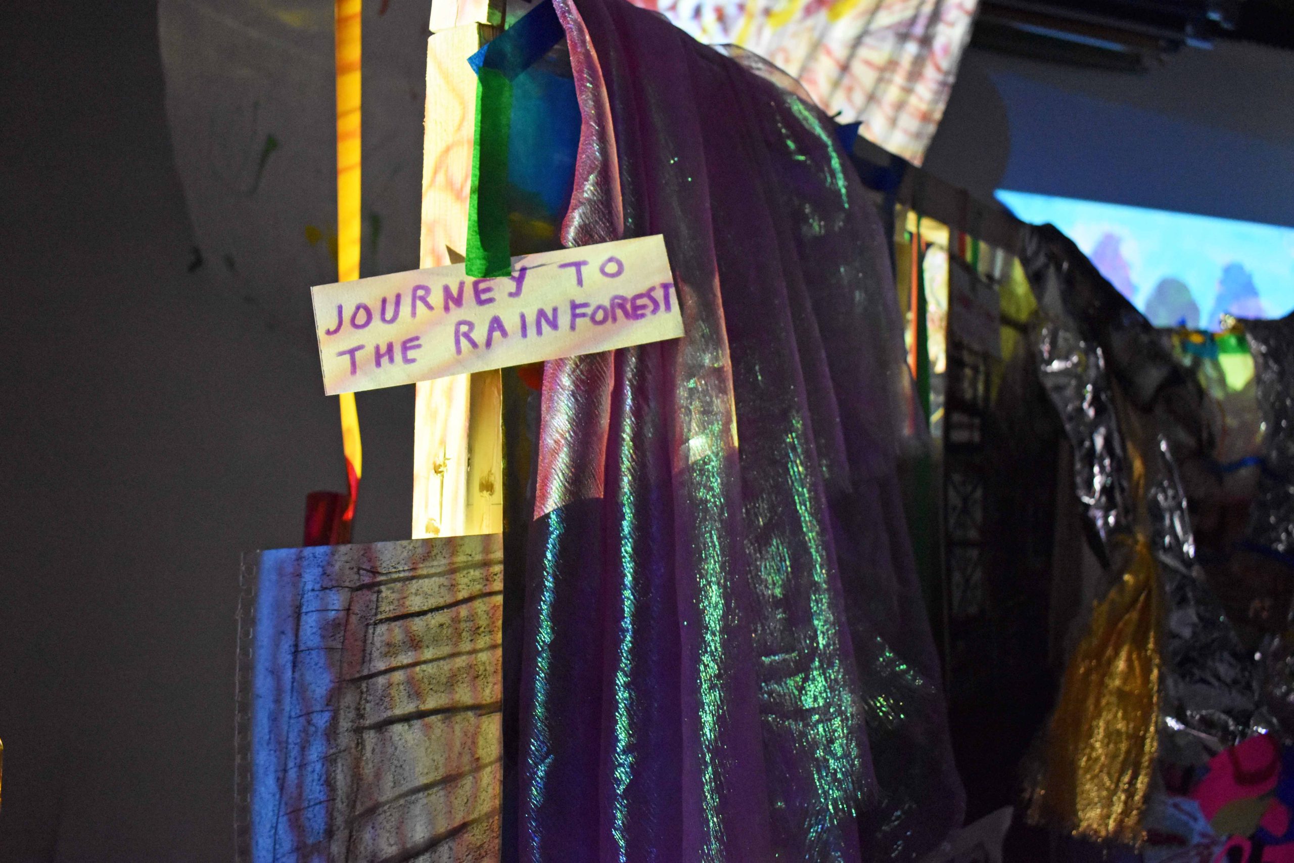 A close up of a mixed media installation, purple writing on brown card reads 'journey to the rainforest'.