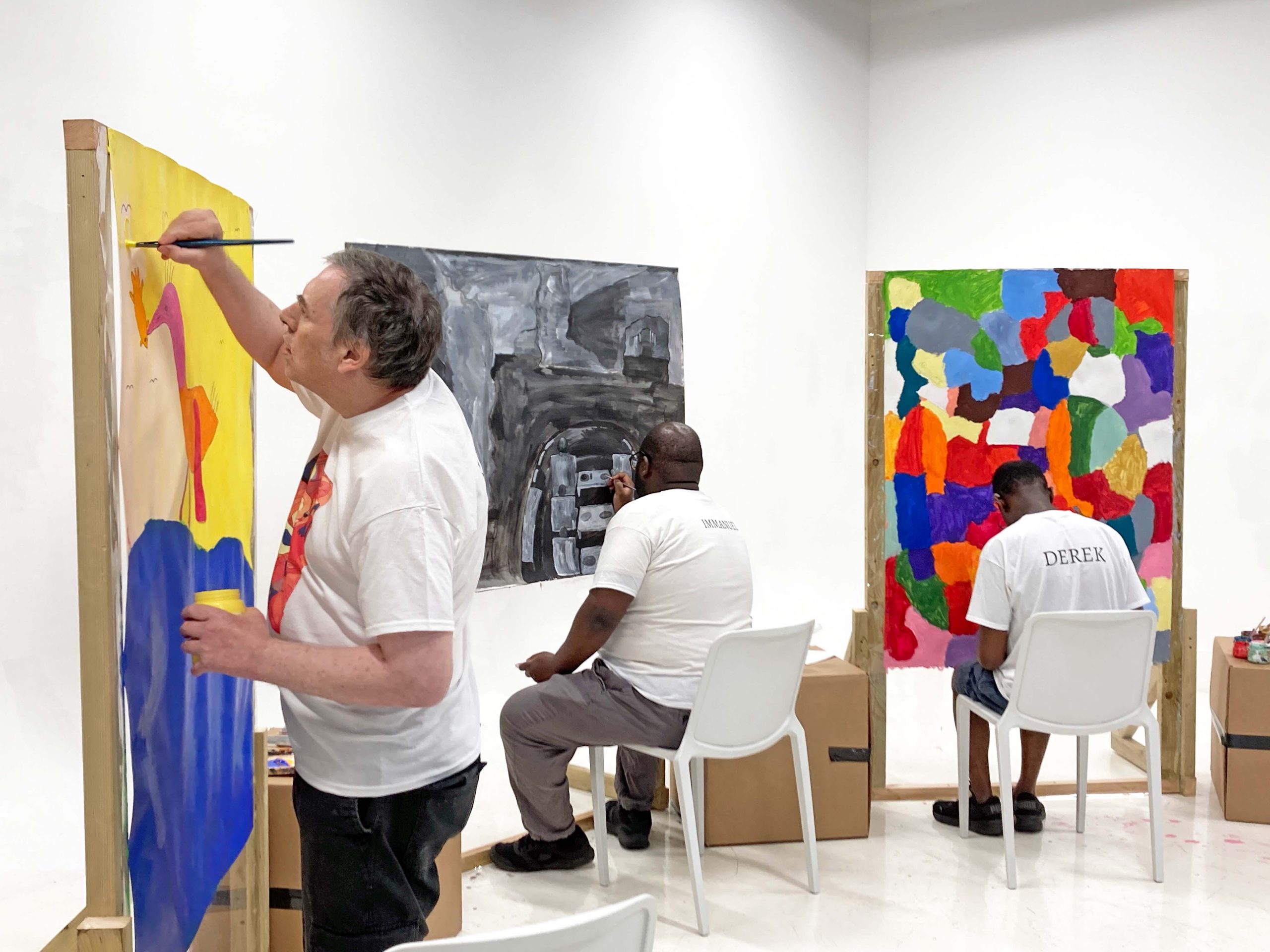 Three male artists busy painting in a white space.