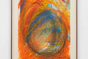 A framed drawing in orange and blue swirls of acrylic and oil pastel on a paper map.